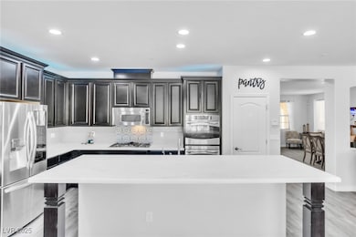 Kitchen featuring stainless steel appliances, a center island, backsplash, recessed lighting, and light wood-style flooring