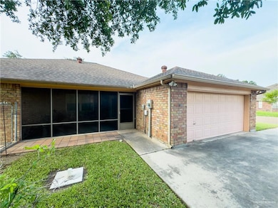 View of front of property featuring aphalt driveway, a shingled roof, brick siding, a sunroom, and a garage