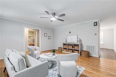 Living room featuring light hardwood / wood-style flooring, ceiling fan, and crown molding