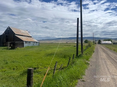View of dirt / gravel road with a barn, a rural view, and a mountain view