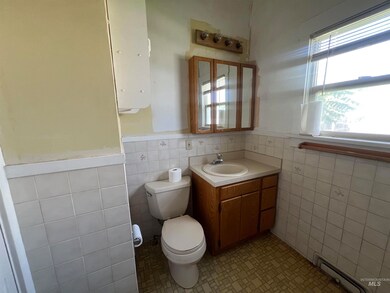Half bathroom featuring a baseboard radiator, tile walls, vanity, and a wainscoted wall