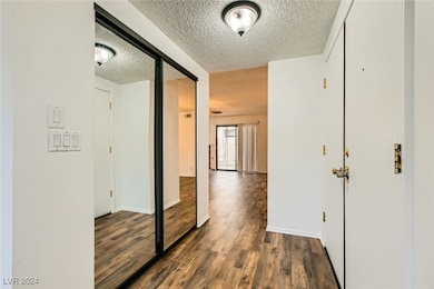 Hallway with a textured ceiling, baseboards, and d