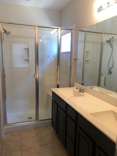 Bathroom featuring a stall shower, double vanity,