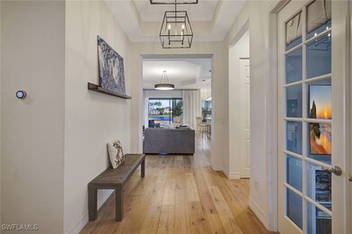 Hallway with light wood-type flooring, a raised ce