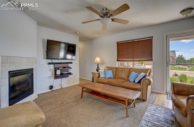 Living area with a tile fireplace and ceiling fan
