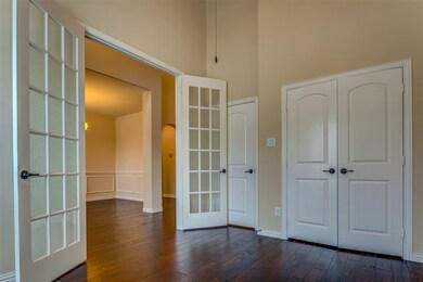 Unfurnished bedroom with arched walkways, dark wood-type flooring, french doors, a high ceiling, and a closet