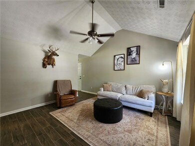 Living room with baseboards, vaulted ceiling, a te