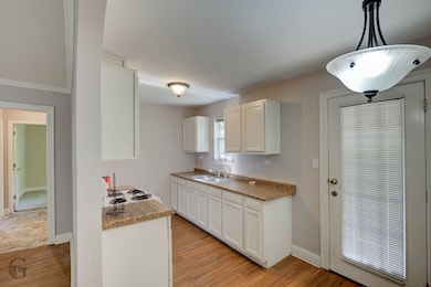 Kitchen featuring white cabinets, light countertops, light wood-type flooring, and hanging light fixtures