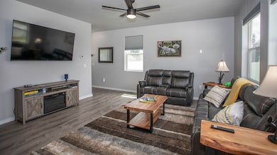 Living room with dark wood-style floors and a ceiling fan