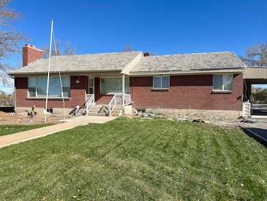 Ranch-style house featuring brick siding, a front lawn, a chimney, a tiled roof, and a porch