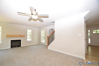 Unfurnished living room with stairs, healthy amount of natural light, a ceiling fan, and a glass covered fireplace