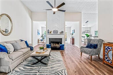 Living area featuring plenty of natural light, wood finished floors, a large fireplace, ceiling fan, and lofted ceiling