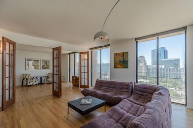 Living area with french doors, light wood-type flooring, a skyline view, and floor to ceiling windows