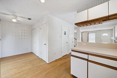 Kitchen featuring white cabinets, light countertops, light wood finished floors, brown cabinets, and a textured ceiling
