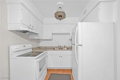 Kitchen featuring white appliances, a sink, under