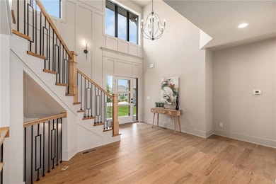 Foyer entrance with light wood-style flooring, healthy amount of natural light, stairway, a towering ceiling, and recessed lighting