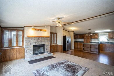 Family room featuring carpet, lofted ceiling, ceiling fan, molding trim, built in shelving, fireplace, and a textured ceiling