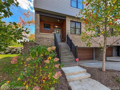 Property entrance featuring brick siding, concrete driveway, and a garage