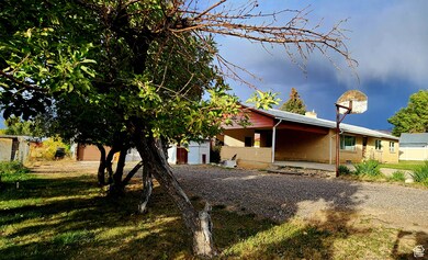 View of front of home featuring an attached carport, gravel driveway, a chimney, brick siding, and a patio area