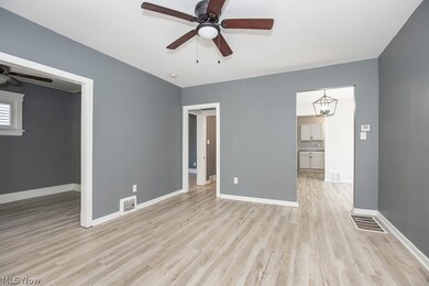 Unfurnished room with ceiling fan with notable chandelier and light wood-type flooring