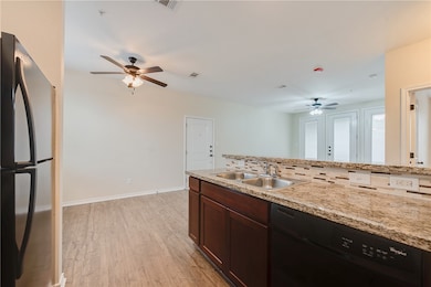 Kitchen featuring a ceiling fan, a sink, backsplas