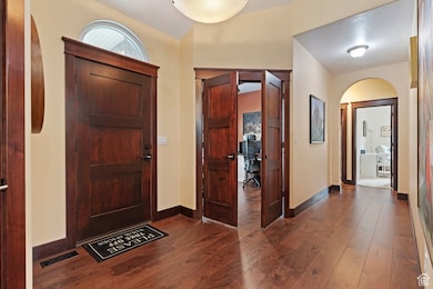 Entryway featuring dark wood-style flooring and arched walkways