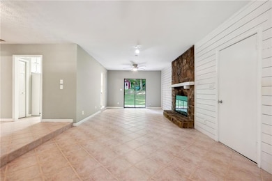 Unfurnished living room featuring light tile patterned flooring, a fireplace, wood walls, and ceiling fan