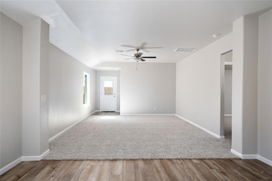 Bright and open living area with plush carpeting, ceiling fan, and direct access to the backyard.