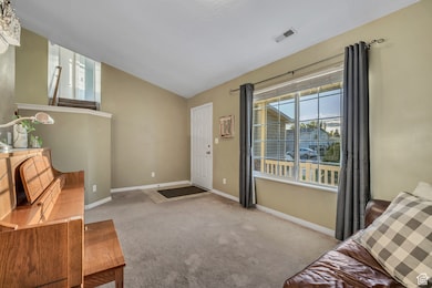 Carpeted living room with lofted ceiling and baseboards