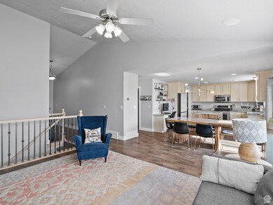 Living room featuring dark wood-style flooring, lofted ceiling, a chandelier, recessed lighting, and a ceiling fan