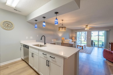 Kitchen with a sink, a textured ceiling, a peninsu