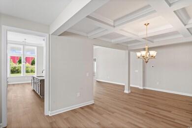 Unfurnished living room with a chandelier, beamed ceiling, light wood finished floors, coffered ceiling, and crown molding