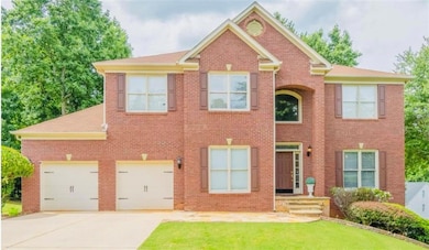 View of front facade featuring driveway, brick siding, and a front yard