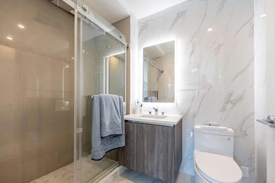 Bathroom featuring vanity, tile walls, a shower stall, and toilet