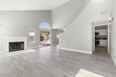 Unfurnished living room with high vaulted ceiling, wood tiled floors, and a tile fireplace