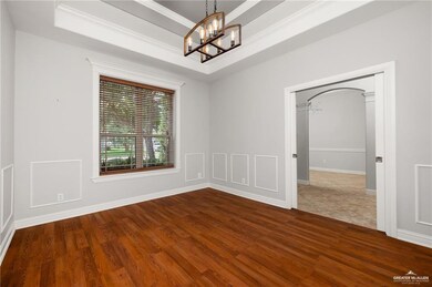 Spare room featuring baseboards, an inviting chandelier, crown molding, and dark wood-type flooring