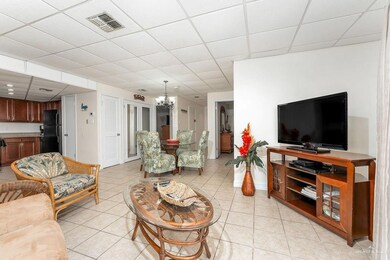 Living room featuring a notable chandelier, a paneled ceiling, visible vents, and light tile patterned floors