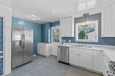 Kitchen with stainless steel appliances, white cabinetry, hanging light fixtures, and a chandelier
