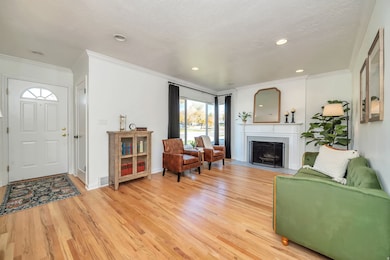 Living area featuring crown molding, light wood finished floors, a fireplace with flush hearth, recessed lighting, and a textured ceiling