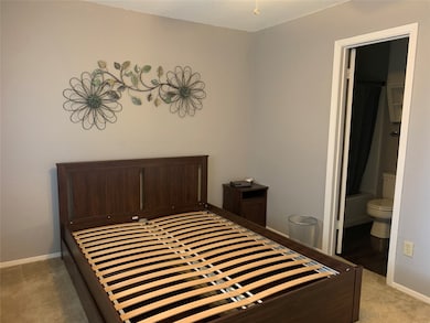 Bedroom featuring light colored carpet and ensuite bathroom