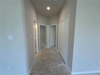 Hallway featuring baseboards and unfinished concre