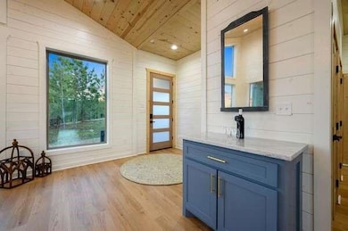 Doorway to outside featuring wood ceiling, wood finished floors, wooden walls, and vaulted ceiling