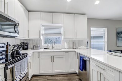 Kitchen with stainless steel appliances, plenty of natural light, recessed lighting, and white cabinetry