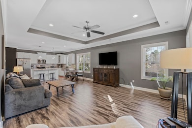 Living room with a raised ceiling, crown molding, and wood-type flooring