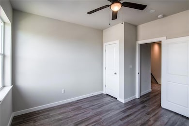Unfurnished bedroom with baseboards, dark wood fi
