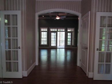Entry hall with a view through the great room to the covered, open back porch. 10' ceilings throughout the main level, except for the 12' ceiling in the great room.  This large foyer has double closets, arched doorways and the French doors from the foyer lead to the library and dining room on either side. Hardwoods flow throughout the downstairs, with carpet in the bedrooms.