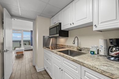 Kitchen with black electric stovetop, sink, a drop