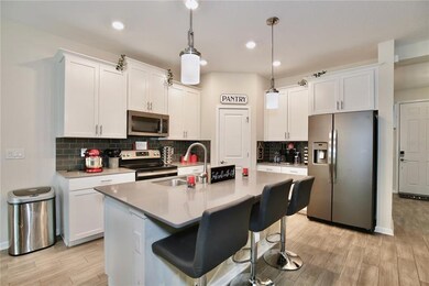 Specious modern kitchen features slate matte finish appliances and roomy pantry.