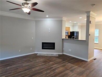 Unfurnished living room featuring crown molding, dark wood finished floors, baseboards, ceiling fan, and a glass covered fireplace