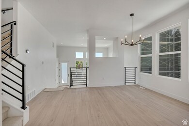 Unfurnished dining area featuring stairway, light wood-type flooring, recessed lighting, and a chandelier